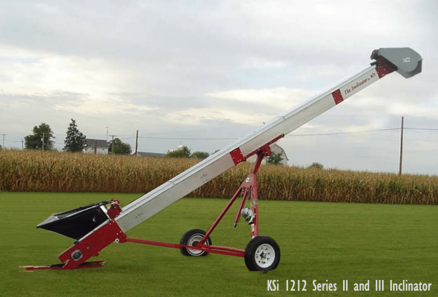 KSi Model 1212 Inclinator Series II and III conveyor on wheeled cart, red frame with silver cleated belt housing, set up in a field